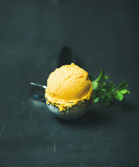 Mango sorbet ice cream scoop in ice cream scooper over black wooden background, close-up. Clean eating, healthy, vegetarian, weight loss, alkaline diet food concept - 158590984