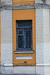 Старое окно с форточкой за решёткой на кирпичной стене