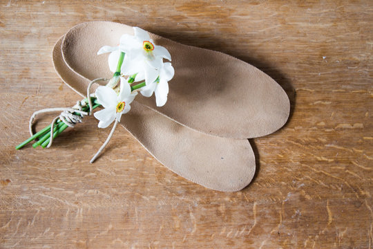 Orthopedic insoles and  bouquet of white daffodils. Wooden background.