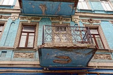 Старый балкон с окнами на голубой кирпичной стене