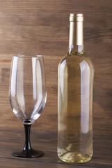 White wine bottle and a glass placed on wooden table. Copy space. Vertical studio shot