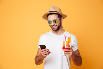 Happy young man chatting by mobile phone holding cocktail.
