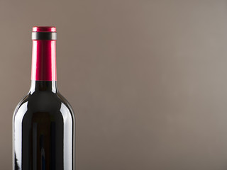 Red wine bottle on gray background Horizontal studio shot. Copy space.