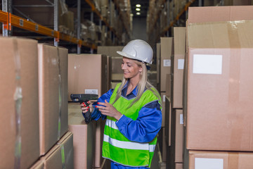 Female warehouse worker using scanner near boxes
