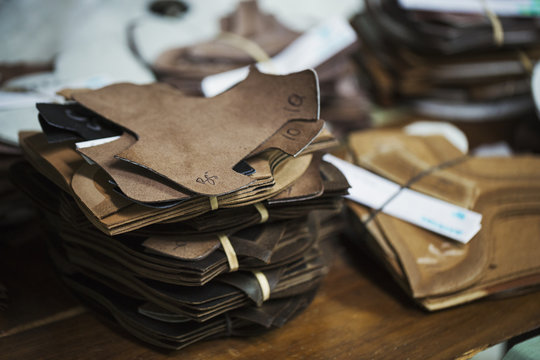 Close up of a stack of brown leather pieces in a shoemaker's workshop.
