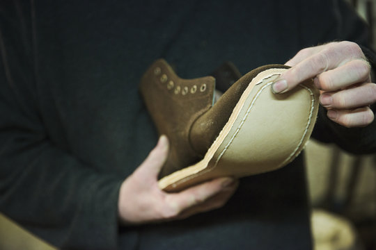 Close up of worker in a shoemaker's workshop, attaching a sole to a leather boot.