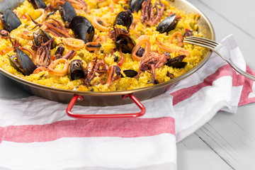 Seafood Paella in Traditional Pan on Rustic Wooden Table
