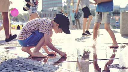 Child playing with water at street fountain
