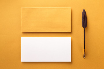 Mockup of envelope, blank white paper and vintage ink pen at golden paper background.