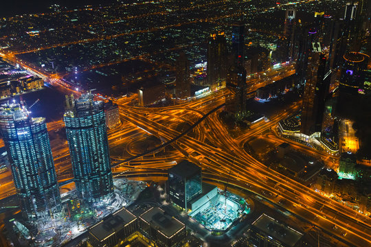 Panoramic aerial view on downtown of Dubai, UAE with modern high skyscrapers at night. Architecture of future with bright lights and roads. United Arab Emirates famous tourist destination