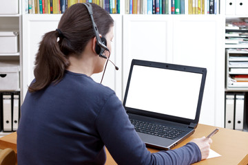 Telework or e-learinig concept: woman with headset and laptop taking notes during a video call or...