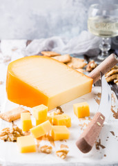 Delicious dutch gouda cheese with cheese blocks, crackers, walnuts and special knife on oud wooden table. Copy space. - obrazy, fototapety, plakaty