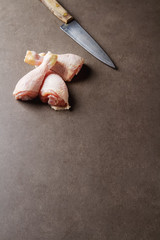 Chicken legs with a knife on a gray background. Lunch on the grill. Space for text. Top view