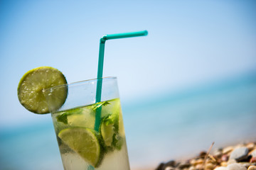 Mojito cocktail with lime and mint in highball glass on beach good as background with copy space