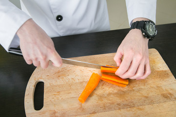 The cook cuts a carrot for ratatouille on a board