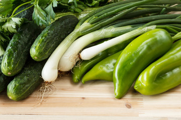 Fresh, organic green vegetables on a wooden background