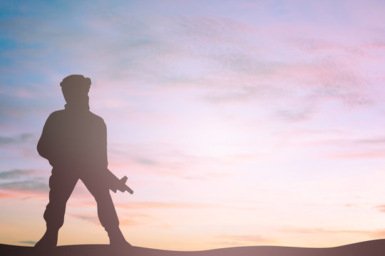silhouette soldier with sniper gun on sunset sky background.