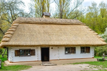 Fototapeta na wymiar National Museum Pirogovo in the outdoors near Kiev. Ancient peasant Ukrainian house in the spring with a thatched roof in the old village of national architecture, Ukraine.