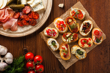 Fototapeta na wymiar Crostini with different toppings on wooden background. Delicious appetizers. Top view.