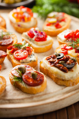 Crostini with different toppings on wooden background. Delicious appetizers. Front view.