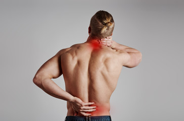 Portrait of athletic male suffering from lumbar vertebrae pain and neck ache. Health care concept. 