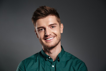 Cheerful young man posing isolated over grey background