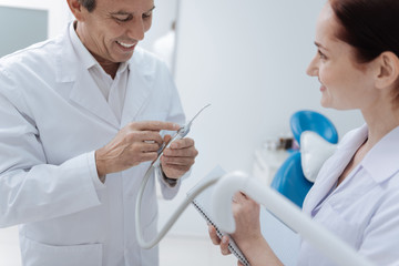 Smiling doctor bowing head while demonstrating equipment