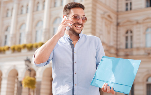 Portrait of a young businessman with mobile phone and folder. Education, business, lifestyle concept