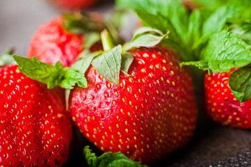 Strawberry with mint lies on a concrete gray background. Food in the macro. Strawberries with powdered sugar