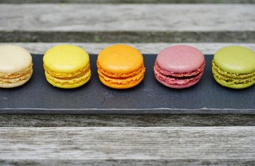 Colorful round macaron cookies on a black slate platter
