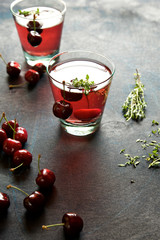 Homemade cherry lemonade with thyme on a dark blue background 
