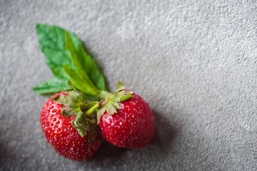 Strawberry with mint lies on a concrete gray background. Food in the macro. Strawberries with powdered sugar