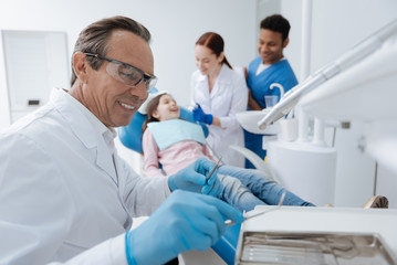 Portrait of positive dentist that taking sterile instruments