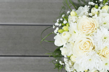 white fresh roses, freesia and mum flowers wedding bouquet on wooden background close up