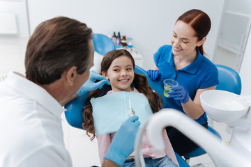 Little positive kid with curly hair smiling to her doctor