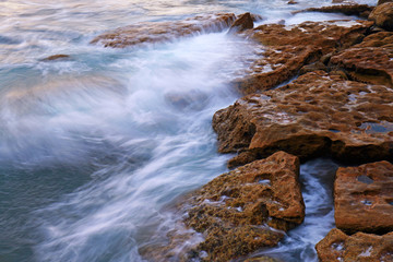 Waves flow into rock formation.