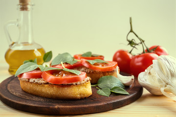 Bruschetta with liver pate, tomatoes and basil on a wooden board. Traditional Italian snack. Close-up.
