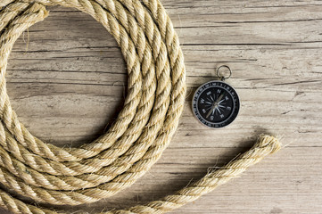Close up shot of a compass and a rope on wood background