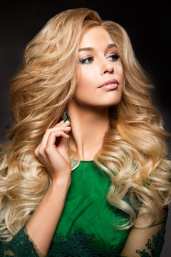 Portrait of elegant sexy blonde woman with long curly hair and glamour makeup. Lady looking at camera.