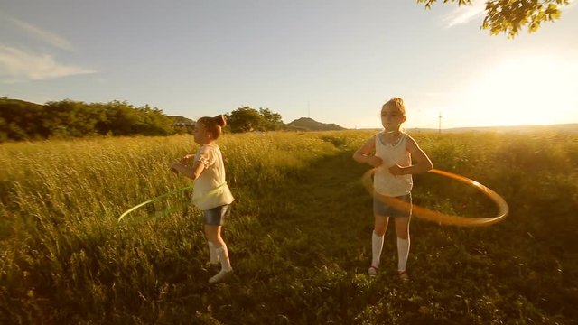 Two kids girls play with hula-hoop