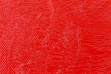 Wet red paint on an artist canvas close view.
