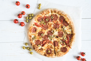top view of homemade italian pizza with cherry tomatoes and olives on wooden surface