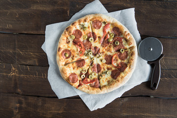 top view of italian pizza on baking paper and pizza cutter