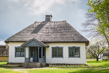 Fototapeta na wymiar National Museum Pirogovo in the outdoors near Kiev. Ancient peasant Ukrainian house in the spring with a thatched roof in the old village of national architecture, Ukraine.