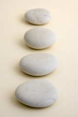 Row of white zen stones on wooden mat, four pebbles in a row, massage and relaxation