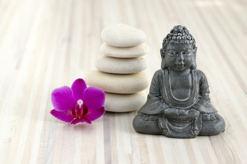 Small Buddha sculpture, pebbles cairn, five white stones, one purple phalaenopsis orchid flower