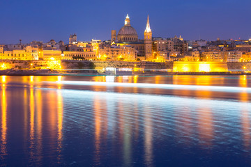 Obraz premium Valletta Skyline from Sliema with church of Our Lady of Mount Carmel and St. Paul's Anglican Pro-Cathedral during evening blue hour, Valletta, Capital city of Malta