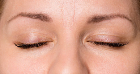 Close-up face of beautiful young woman with beautiful big eyelashes and eyebrows. Macro of human eye - close.