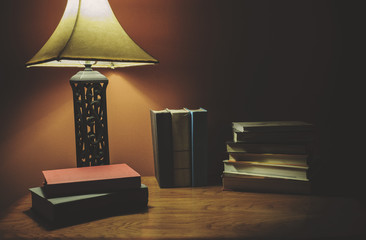 Stack Of Hardcover Books On A Wood Table With Lamp