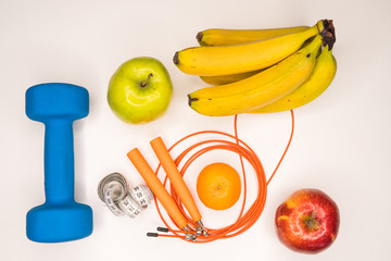 healthy eating concept. Dumbbell, rope, bananas, orange, measuring tape waist, oranges, red apple, green apple, on a white table. healthy lifestyle. sport. Fitness diet
